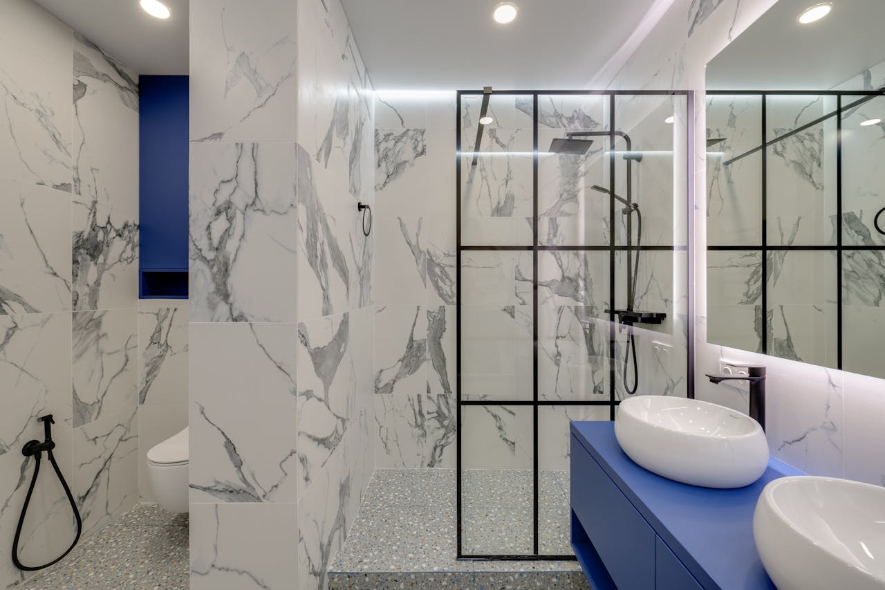 Mastering the First Impression: Your intriguing post title goes here Elegant bathroom featuring marble walls, double sinks, and a glass-enclosed shower.